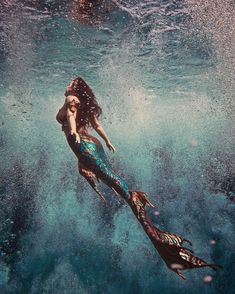 a woman is swimming in the ocean with her long hair blowing up into the air