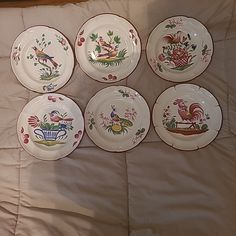 six plates with different designs on them sitting on a bed