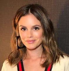 a woman with shoulder length hair standing in front of a wall