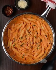 a pan filled with pasta and sauce on top of a wooden table