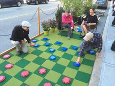 three people playing checkers on a green and blue board with red circles in the middle