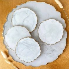 three white plates sitting on top of a wooden table next to dried flowers and leaves