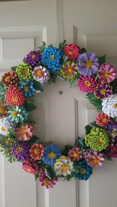 a wreath made out of paper flowers on the front door to decorate it for someone's house