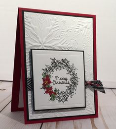 a handmade christmas card with a wreath and poinsettis on the front