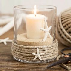 a candle that is sitting inside of a glass cup with rope and starfish on it