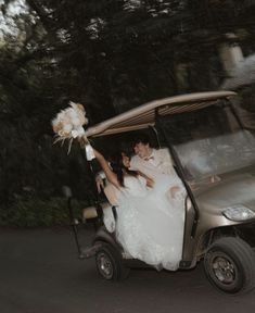 a bride and groom riding in a golf cart