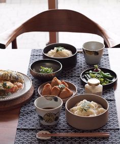 a table topped with bowls filled with food next to chopsticks and saucers