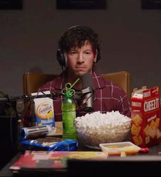 a man wearing headphones sitting at a table in front of a bowl of rice