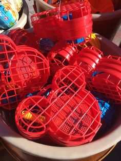 several red plastic cages sitting on top of a white bowl filled with orange and blue toys