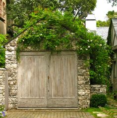 an old stone building with two wooden doors and brick walkway leading up to the front door