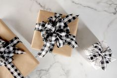 two wrapped presents with black and white bows on them sitting on a marble counter top