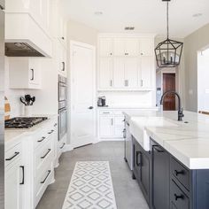 a large kitchen with white cabinets and marble counter tops, along with an area rug on the floor