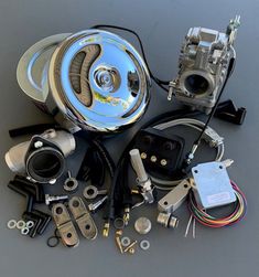 an assortment of carburets and parts on a gray surface, including the engine