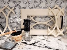 a marble counter top with an ornate frame and paint can next to it on the counter