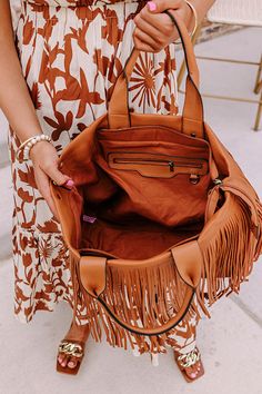 - Faux leather material with fringe trim detail - Brass hardware - Two tote handles as well as a detachable adjustable shoulder strap - A spacious fully lined pouch with three additional inside pockets - Zip closure Brown Tasseled Bags For Shopping, Brown Fringe Bag For Everyday Use, Brown Tassel Bags For Shopping, Brown Fringe Bag For Fall, Brown Shopping Bags With Tassels, Fringe Bags For Everyday Use In Fall, Brown Fringe Tote Shoulder Bag, Brown Fringe Bags For Daily Use, Brown Satchel Bag With Fringe