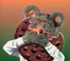 a person wearing a mouse mask holding a cookie