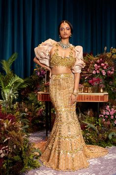 Introducing our "Golden Glamour Lehenga" - a stunning mermaid lehenga embellished with golden metals, sequins, and dangling chains. The tube blouse features intricate jhaali work with elegant latkans, paired with a hand draped jacket for an extravagant touch. Experience the allure of opulence and grace in this mesmerizing ensemble, designed to make you shine on your special day. Colour: Gold Fabric: Tulle Technique: Hand Embroidery No of set: 3 Delivery Time: 8-10 weeks Washcare: How to Store yo Traditional Luxury Gold Embroidered Dress, Luxury Traditional Wear With Gold Embroidery, Luxury Gold Traditional Wear With Intricate Embroidery, Luxury Gold Traditional Wear With Weaving Work, Luxury Bollywood Gown With Gold Embroidery, Luxury Bollywood Dress With Intricate Embroidery, Luxury Gold Embroidered Lehenga For Navratri, Luxury Traditional Wear With Gold Embroidery For Festivals, Heeramandi Costumes