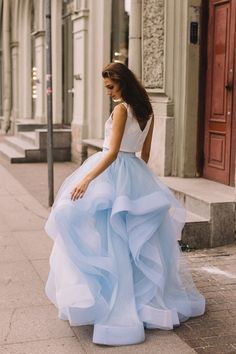 a woman in a blue dress is standing on the sidewalk