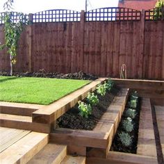 an outdoor garden with wooden steps leading up to the grass area and fenced in back yard