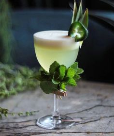 a glass filled with a drink sitting on top of a wooden table next to plants