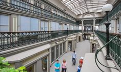 three people are walking down an indoor walkway