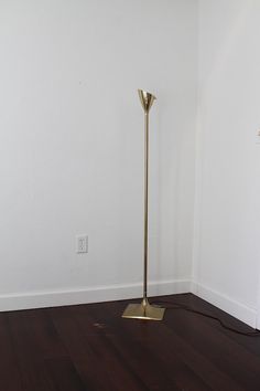 a floor lamp in the corner of a room with hard wood floors and white walls