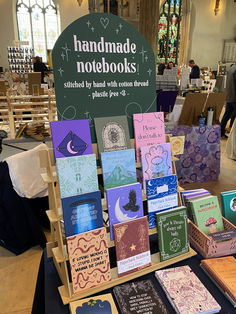 there are many books on display at the book sale in the church lobby, with handmade notebooks written by hands with cotton thread