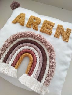 an embroidered pillow with the word arren on it and a rainbow in the middle