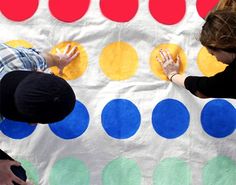 two people standing next to each other with their hands on a large polka dot blanket