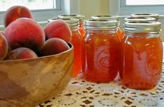 peaches in jars sit on a table next to a bowl of peaches