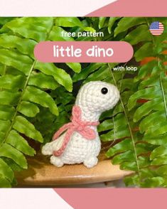 a crocheted little dino sitting on top of a table next to some plants