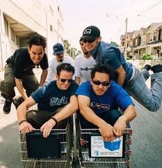 four men are riding in the same shopping cart