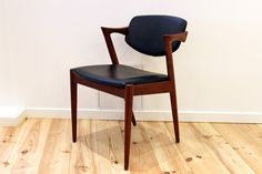 a wooden chair sitting on top of a hard wood floor next to a white wall