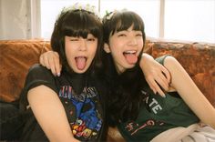 two young women sitting on top of a couch with their mouths open and tongue out