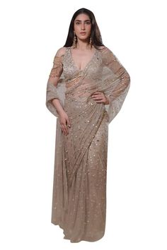 Beige pre-draped net saree with all over tonal sequin sitara embellishments. Paired with a cold shoulder cutdana, sequin, mirror embroidered V neck blouse with dangling glass bead tassel embellishments. - Aza Fashions Elegant Sequined Blouse With Traditional Drape, Evening Hand Embellished Blouse Traditional Drape, Evening Hand Embellished Traditional Blouse, Glamorous Draped Designer Dress, Elegant Hand Embellished Draped Saree, Elegant Draped Blouse With Sequins, Elegant Floor-length Embellished Blouse, Elegant Draped Sequin Blouse, Festive Embellished Draped Blouse