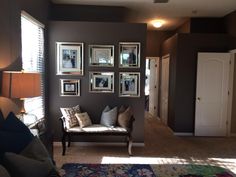 a living room filled with furniture and framed pictures on the wall above it's doorway