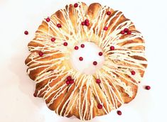 a pastry with white icing and pomegranates on it sitting on a table