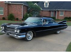 an old black car parked in front of a house