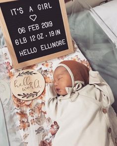 a baby is sleeping next to a sign that says it's a girl