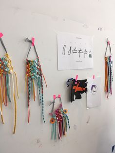 several pieces of art hanging on a wall with paper clips attached to the side of it