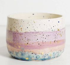 a white and pink bowl with gold speckles on the outside, sitting on a table