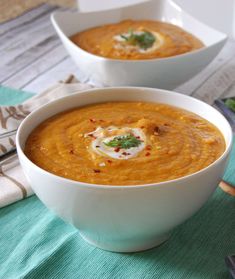 two white bowls filled with soup on top of a table