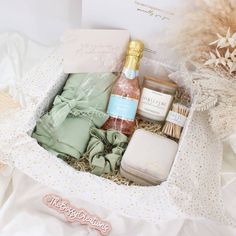 an open gift box containing body care products and personal care items on a white bed