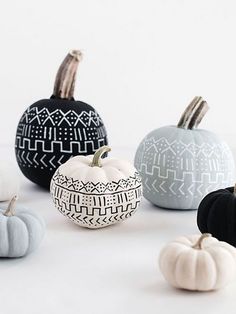 several painted pumpkins sitting on top of a white table next to eachother