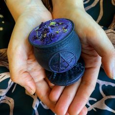 a person holding a purple pot with stars on it in their hands and the lid is open