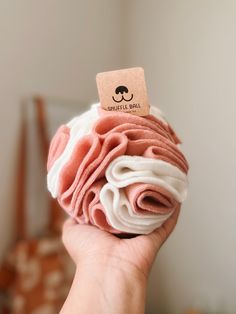 a person holding up a pink and white cupcake