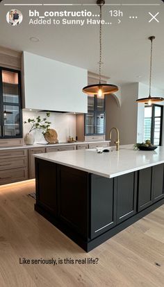 a large kitchen with an island in the middle and two pendant lights hanging from the ceiling