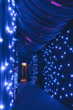 a man standing in front of a blue curtain covered tunnel with lights on the walls