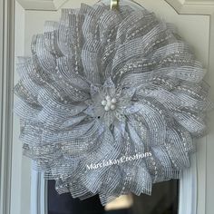 a wreath hanging on the front door of a house with silver mesh flowers in it