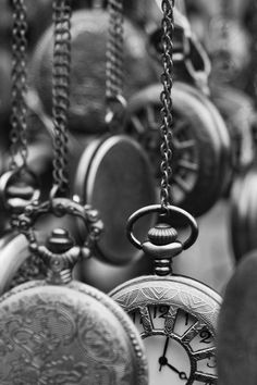 black and white photograph of many different pocket watches hanging from chains with chain links attached to them